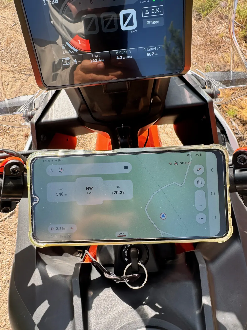 A Samsung Android phone in a rugged case, mounted in landscape orientation on a motorcycle, running OffTrail navigation with an altitude and compass HUD.